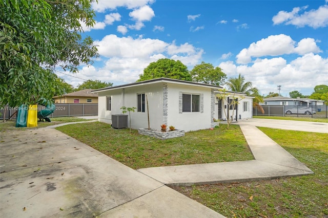 ranch-style home with a front lawn and central air condition unit