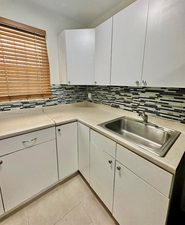 kitchen featuring backsplash, white cabinetry, sink, and light tile patterned floors