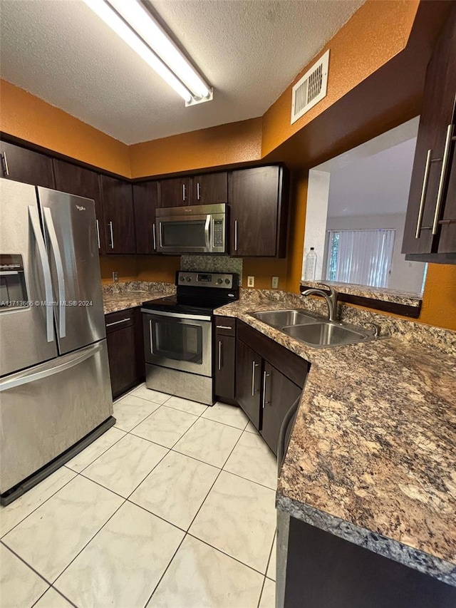 kitchen featuring dark brown cabinets, stainless steel appliances, a textured ceiling, and sink