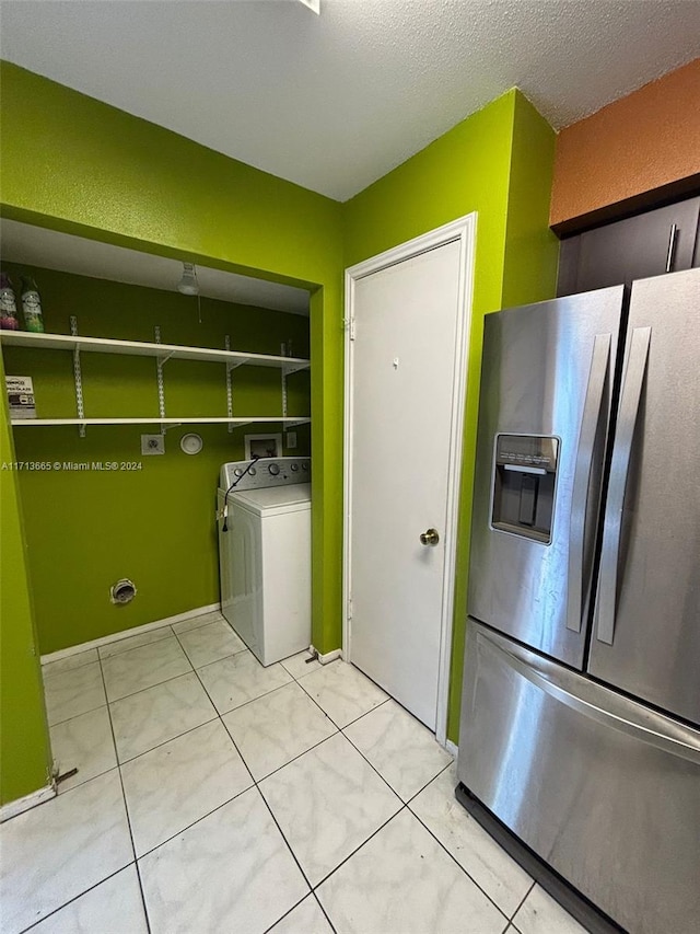 laundry area featuring a textured ceiling, washer / clothes dryer, and light tile patterned flooring