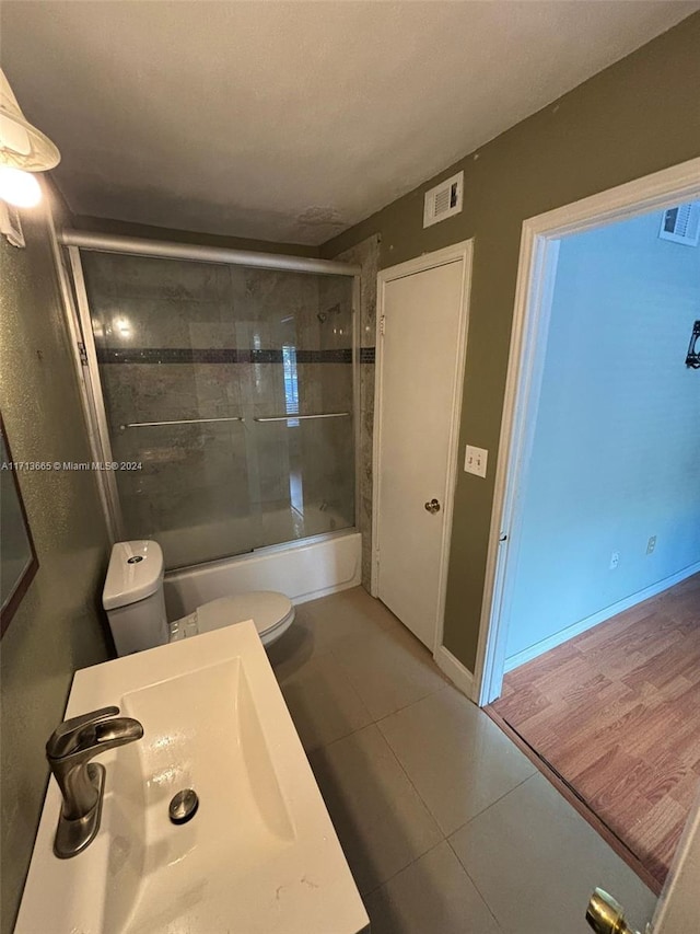 full bathroom featuring sink, tile patterned flooring, enclosed tub / shower combo, and toilet