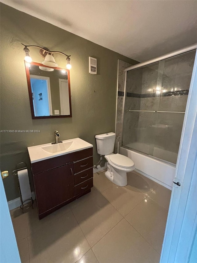 full bathroom with tile patterned flooring, toilet, combined bath / shower with glass door, and vanity