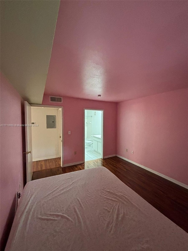 unfurnished bedroom with electric panel, ensuite bathroom, and hardwood / wood-style floors