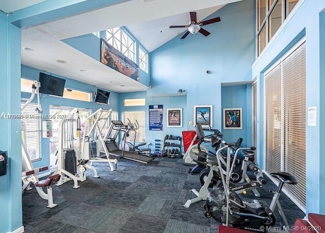 workout area with a wall mounted AC, ceiling fan, a towering ceiling, and dark carpet