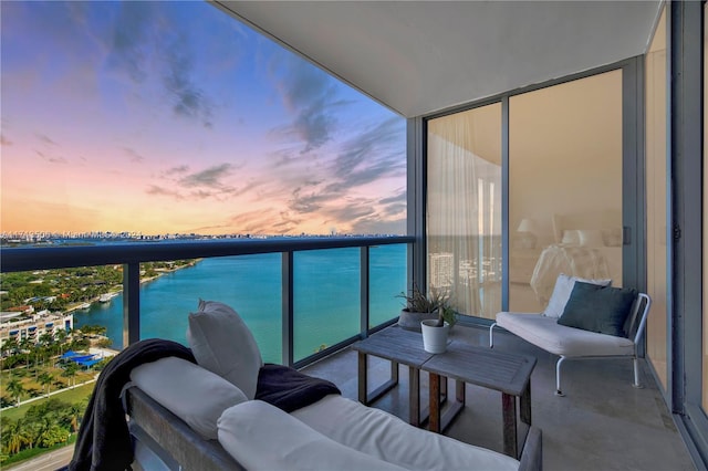 balcony at dusk featuring a water view