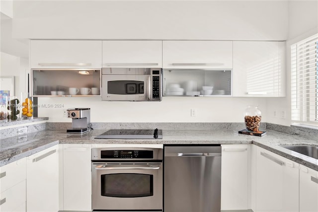 kitchen with light stone counters, sink, white cabinets, and appliances with stainless steel finishes