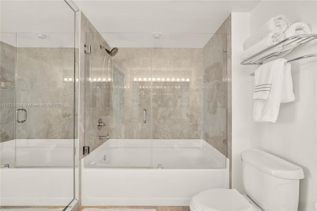 bathroom featuring toilet and bath / shower combo with glass door