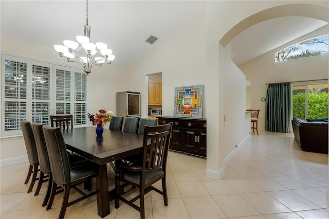 dining area with high vaulted ceiling, an inviting chandelier, and light tile patterned flooring