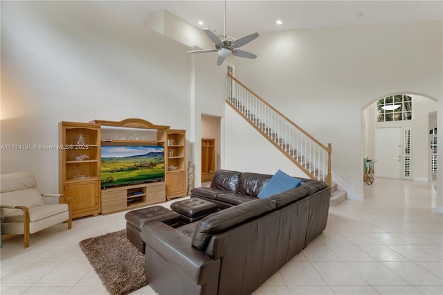 tiled living room featuring ceiling fan and a towering ceiling