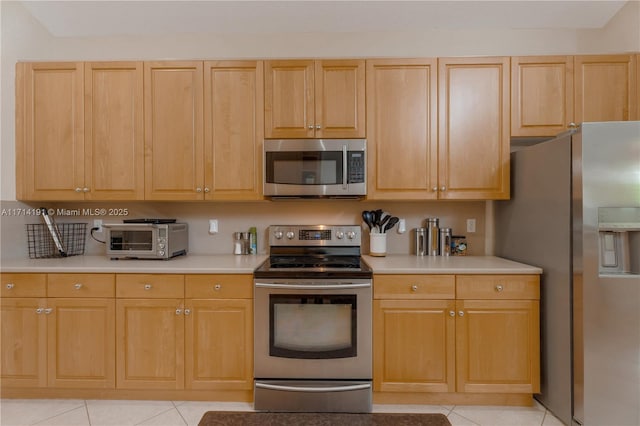 kitchen with light brown cabinets, light tile patterned floors, and appliances with stainless steel finishes