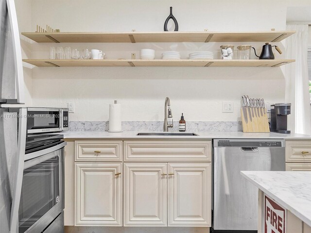 kitchen with light stone counters, sink, and stainless steel appliances