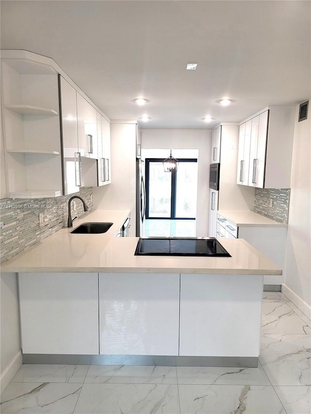 kitchen with kitchen peninsula, stainless steel appliances, sink, an inviting chandelier, and white cabinetry