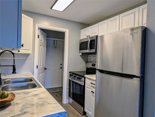 kitchen with white cabinets, appliances with stainless steel finishes, light wood-type flooring, and sink