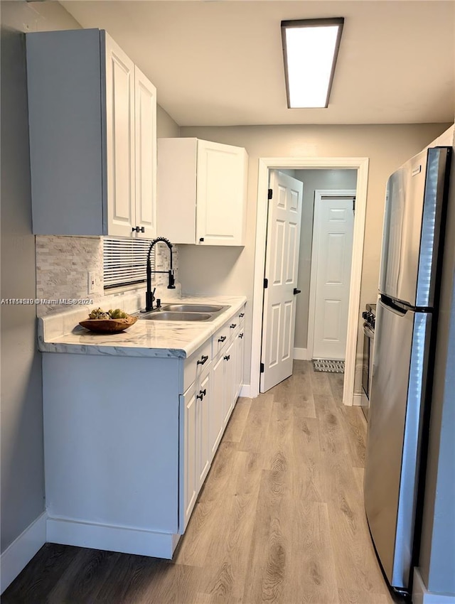 kitchen featuring white cabinetry, stainless steel fridge, sink, and light hardwood / wood-style flooring