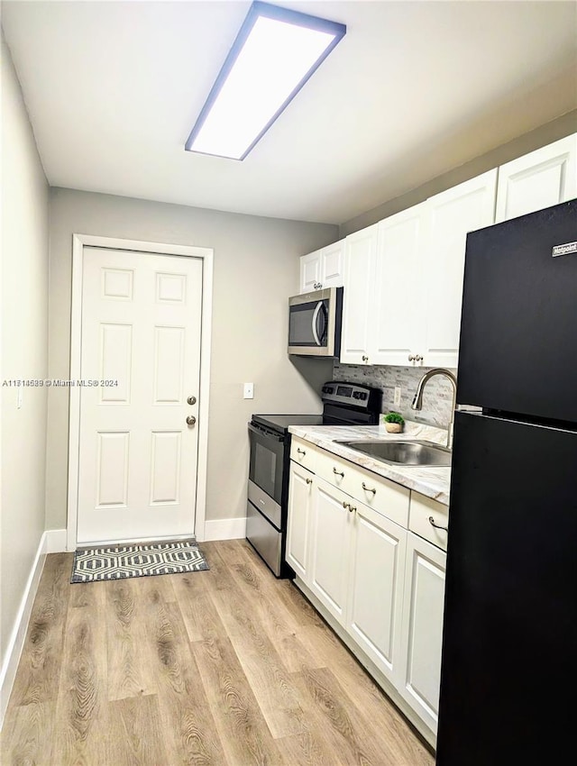 kitchen featuring sink, backsplash, light hardwood / wood-style floors, white cabinets, and appliances with stainless steel finishes