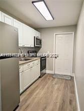 kitchen featuring white cabinetry, sink, light hardwood / wood-style floors, and appliances with stainless steel finishes