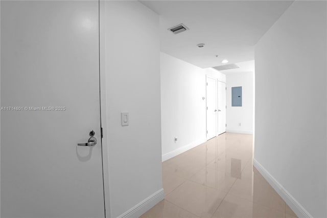 hallway with electric panel, visible vents, and baseboards