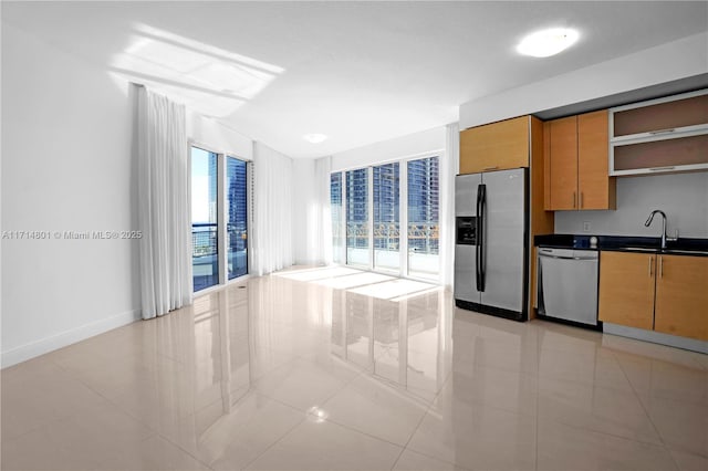 kitchen with stainless steel appliances, a sink, baseboards, open shelves, and dark countertops