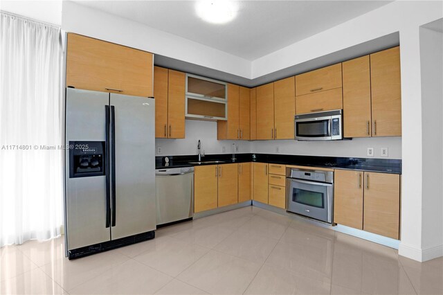 kitchen featuring baseboards, dark countertops, appliances with stainless steel finishes, open shelves, and a sink