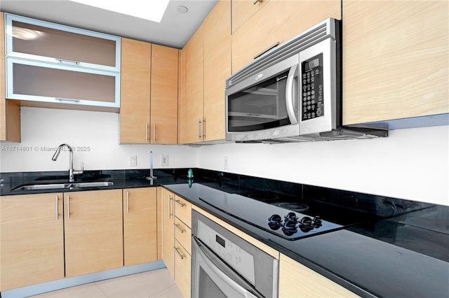 kitchen with black electric stovetop, wall oven, a sink, light brown cabinetry, and stainless steel microwave