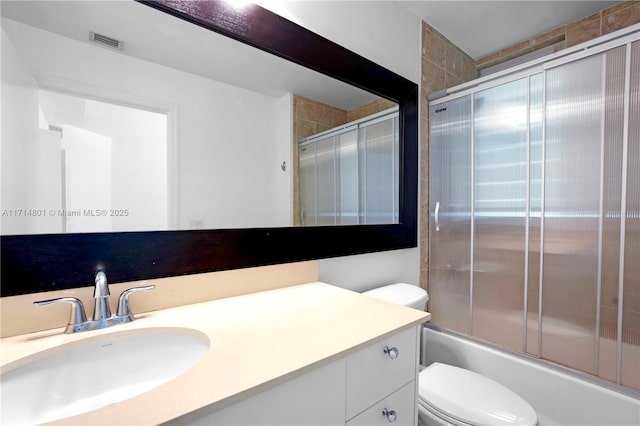 full bath featuring toilet, enclosed tub / shower combo, visible vents, and vanity