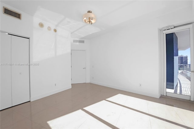 unfurnished bedroom with tile patterned flooring, visible vents, and baseboards