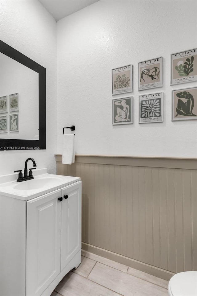 bathroom featuring wainscoting, vanity, and toilet