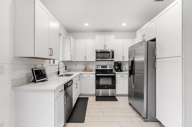 kitchen featuring stainless steel appliances, recessed lighting, light countertops, white cabinetry, and a sink