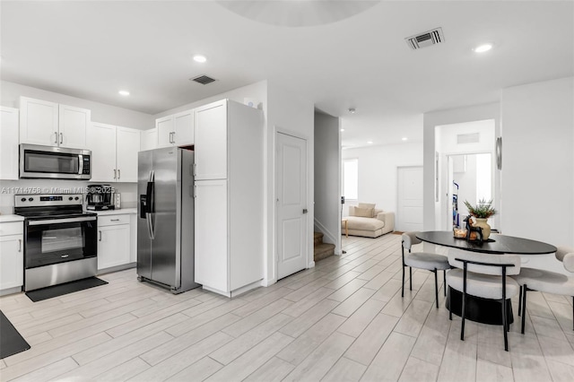 kitchen with white cabinetry, visible vents, stainless steel appliances, and light wood-style flooring