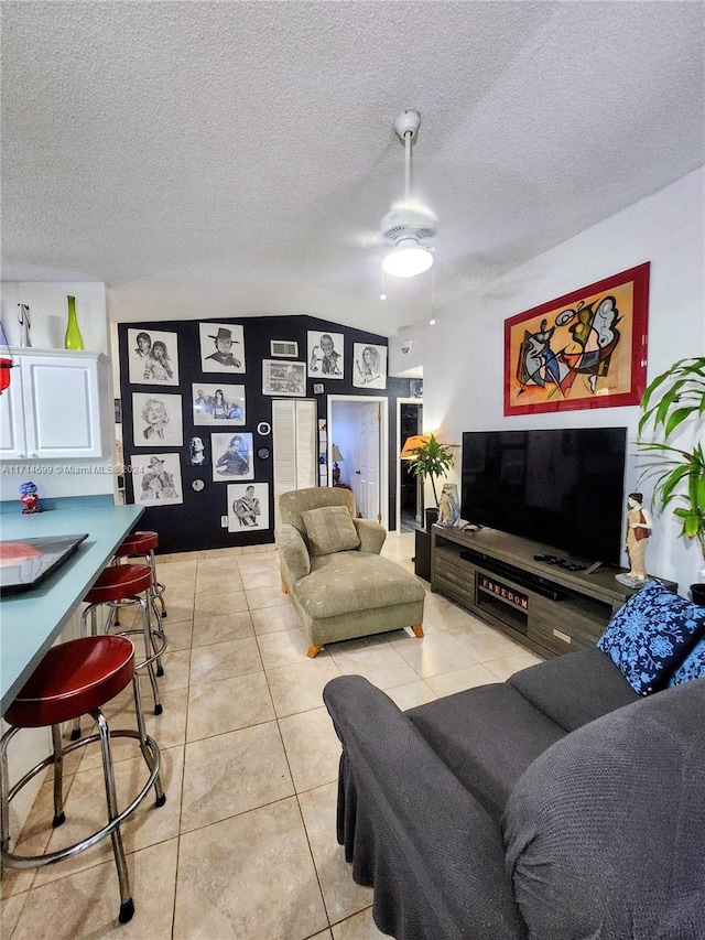 living room featuring a textured ceiling, ceiling fan, lofted ceiling, and light tile patterned flooring