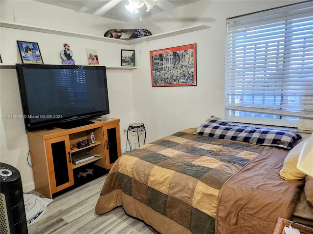 bedroom with multiple windows, ceiling fan, and hardwood / wood-style flooring