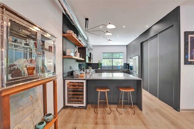 kitchen featuring a kitchen breakfast bar, wine cooler, kitchen peninsula, and light hardwood / wood-style floors