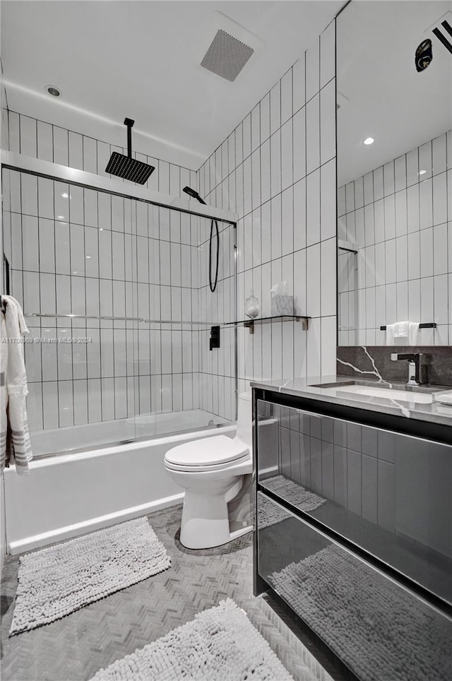 full bathroom featuring tiled shower / bath combo, toilet, tile walls, and vanity