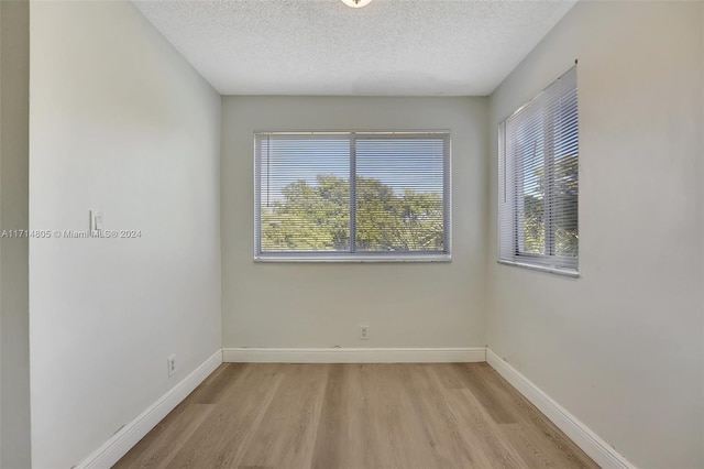 empty room with light hardwood / wood-style flooring and a textured ceiling