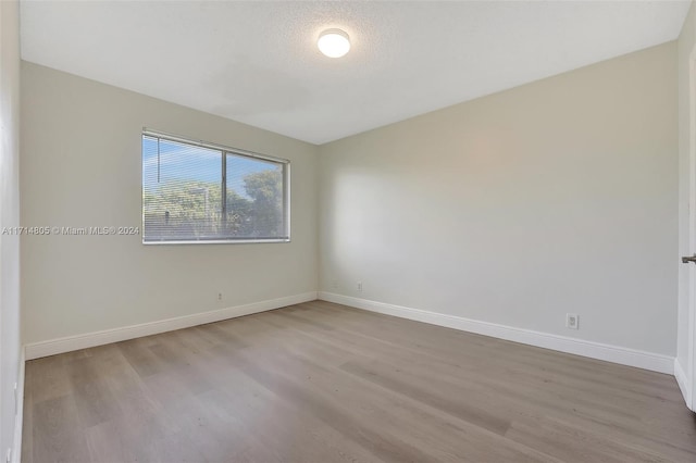 empty room featuring a textured ceiling and light hardwood / wood-style flooring