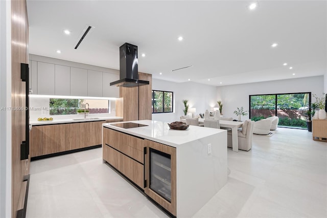 kitchen with sink, a large island, island range hood, and plenty of natural light