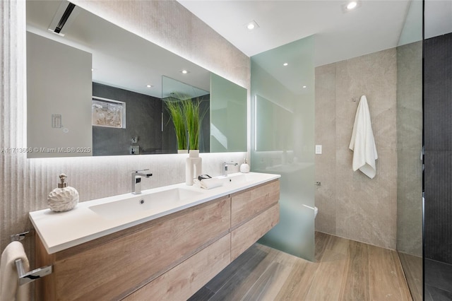 bathroom with hardwood / wood-style flooring, vanity, tile walls, and walk in shower