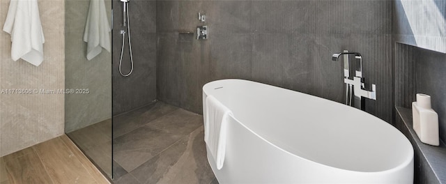 bathroom featuring shower with separate bathtub and tile walls