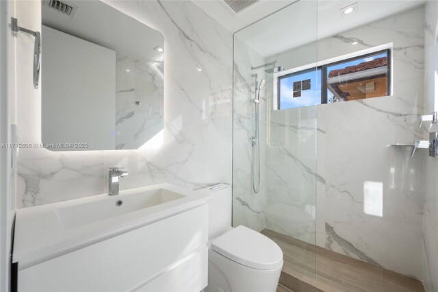 bathroom with tile walls, toilet, vanity, and tiled shower