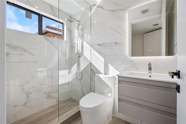 bathroom with toilet, tile walls, wood-type flooring, vanity, and tiled shower