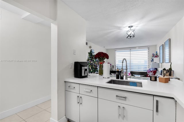 kitchen with white cabinets, light tile patterned floors, a textured ceiling, and sink