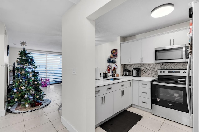 kitchen with white cabinets, sink, light tile patterned floors, and stainless steel appliances