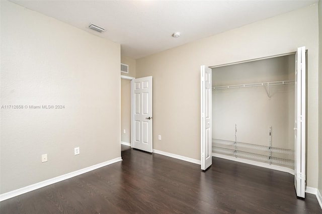 unfurnished bedroom with a closet and dark wood-type flooring