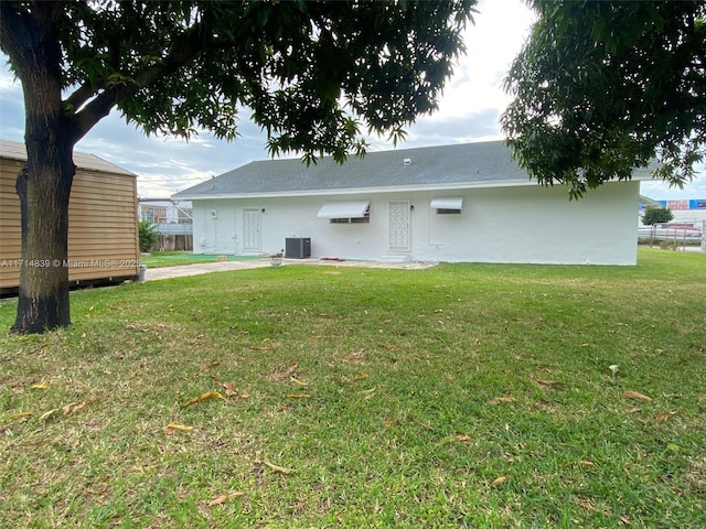 rear view of house with central air condition unit and a lawn