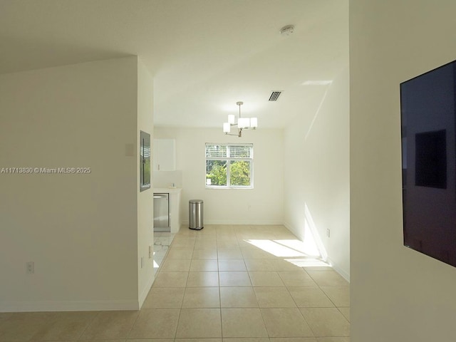 tiled empty room featuring an inviting chandelier