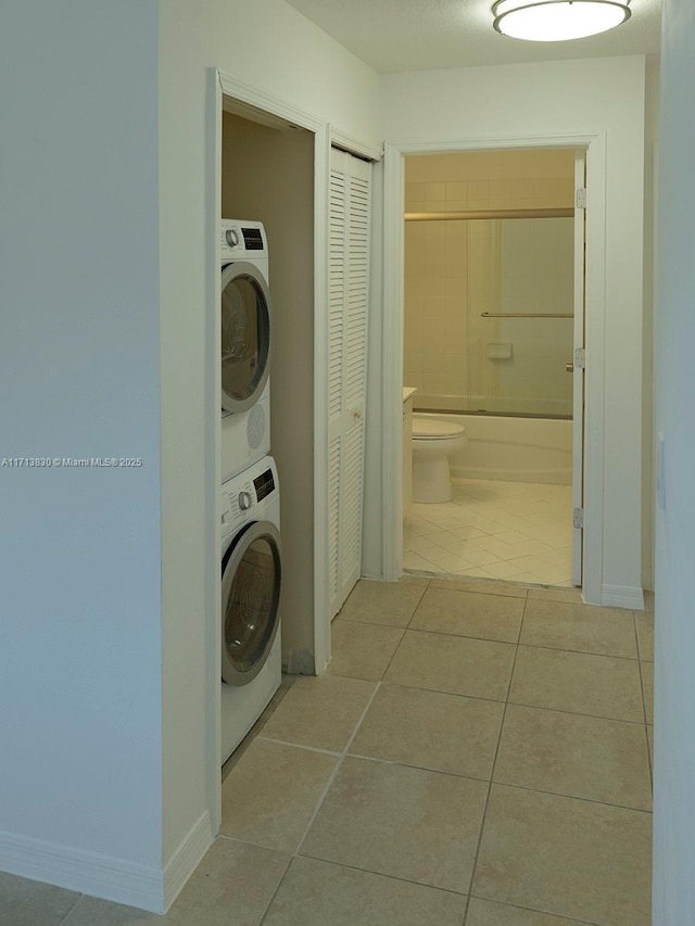 laundry room featuring stacked washer / dryer and light tile patterned floors