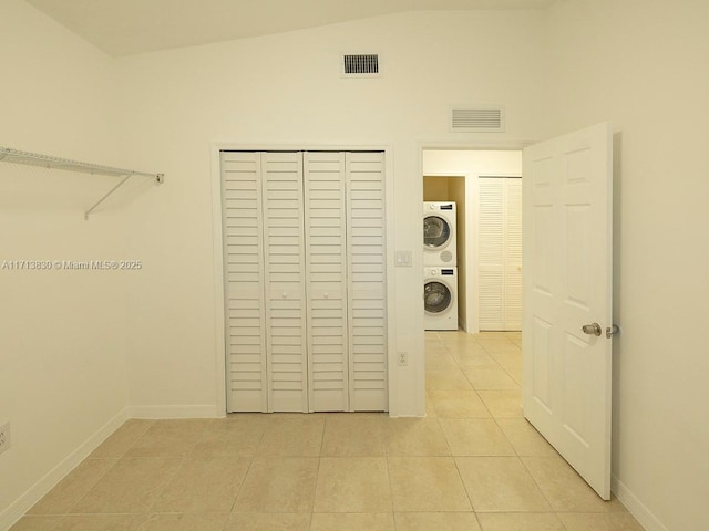 clothes washing area featuring light tile patterned floors and stacked washer and dryer