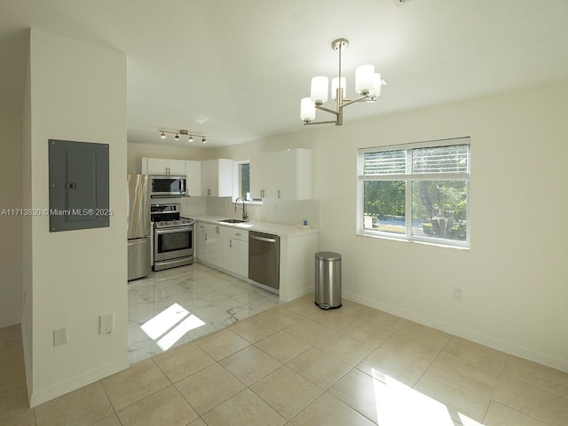 kitchen with appliances with stainless steel finishes, hanging light fixtures, a chandelier, white cabinets, and sink