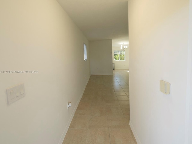 hall featuring light tile patterned floors and a chandelier