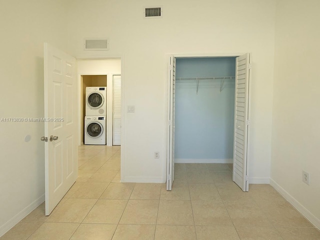 unfurnished bedroom featuring stacked washer and dryer, a closet, and light tile patterned flooring